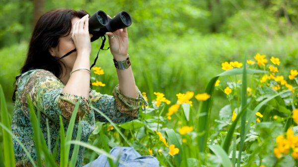 Image via Shutterstock Woman looking through binoculars