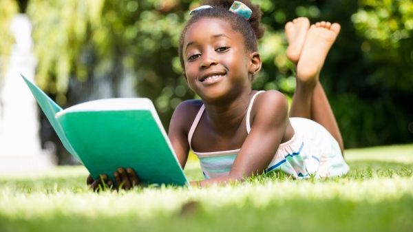 young child reading in grass