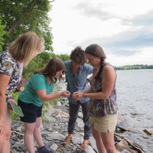 A group of educators learning on a rocky lakeshore