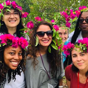 Photo of six people with pink flowers in their hair.