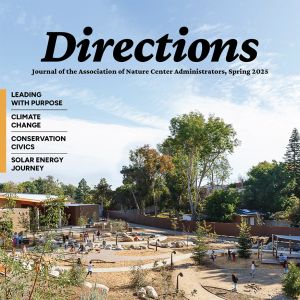 The cover of the Directions journal: A photo of children playing outdoors amid a winding path and sparse, desertous plants. In the background, a building stands amid trees.