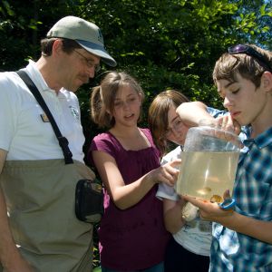 A group of students examine a large sample of water from the Karnowsky Creek with US Forest Service Water Scientist at Karnowsky Creek on the Siuslaw National Forest