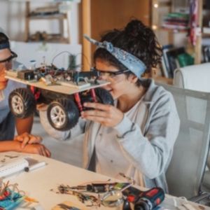 Two people building an electric vehicle model using recycled materials 