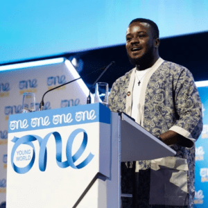 A banner showing a male speaker on stage at the 2025 One Young World Summit