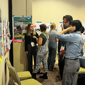 A group of NAAAEE 2024 attendees look at posters at the CEE-Change Workshop gallery walk
