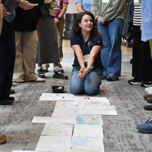 The image shows an educator in the middle of a crowd teaching