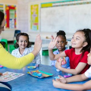 Teacher high-fiving four smiling students