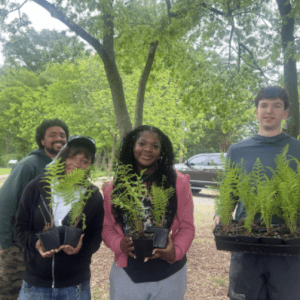 Future Leaders of Our Waters Fellowship Program graphic with a group of students in the background. Three students hold plants from a service project.