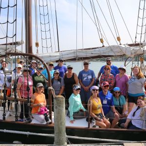 A group of teachers smile while sitting on the deck of a tallship schooner.