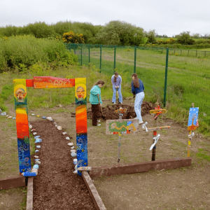 Three kids dig into the soil of a garden
