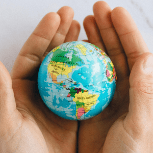 Two hands cradle a small globe against a white background