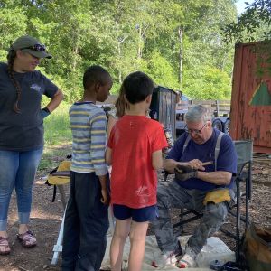 Image of two children observing an adult at forest school