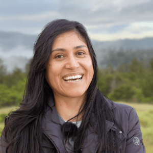 Photo of Blanca Hernández smiling outside in a verdant hilly area