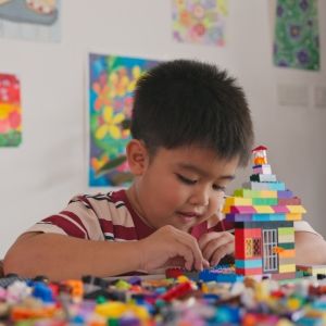 Two children play with plastic building blocks on a table.