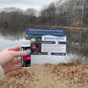 a volunteer holds their Nitrate Watch kit in front of a body of water