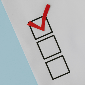 Part of a piece of paper is seen above a light blue background; the paper has three checkboxes, the top one filled in with a red check mark