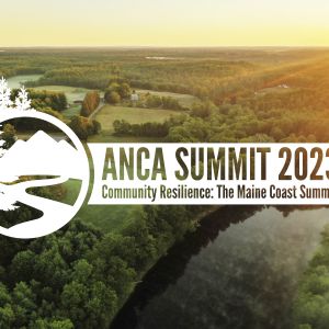 A white logo with a backdrop of an aerial landscape photo. The logo says "ANCA Summit 2023 — Community Resilience: The Maine Coast Summit." The backdrop photo is an aerial picture of a sunrise over mostly forested land, with a river in the bottom right corner.