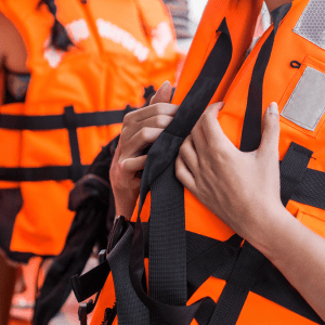 Zoomed in on two people in bright orange life vests, view of heads cut off by the image ending