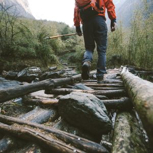 A hiker walking across a wooden bridge