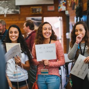 Group of students at an environmental conference holding up a sign that says "Live a Plastic Free Life" 