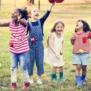 A group of children line up outdoors with a green field behind them