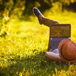 Person lying down on grass With laptop. 
