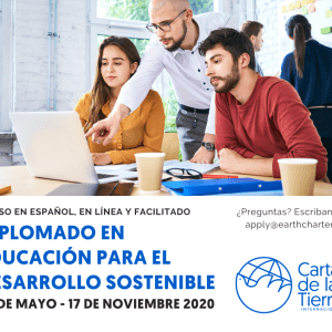 Instructor stands between two students, pointing at a computer screen