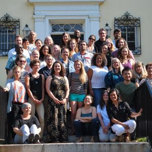 group of ee360 Fellows standing and sitting on stairs in front of yellow building