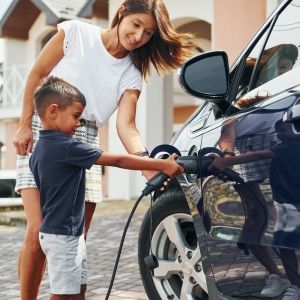 A woman and young boy plug in an electric vehicle 