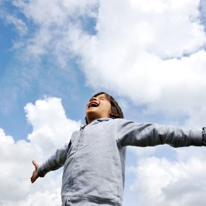 Young student reaching out and looking at sky