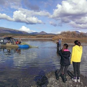 Two kids at the beach watch a boat pull onto a shallow beach