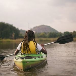 A person in a yellow life jacket paddles in a kayak