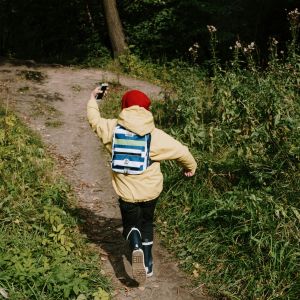 A child running on a dirt pathway while holding a phone