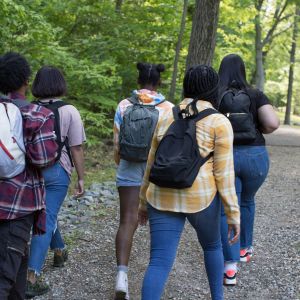 Group of five teenagers walking on a forested path