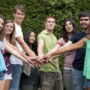 A group of young adults putting their hands together