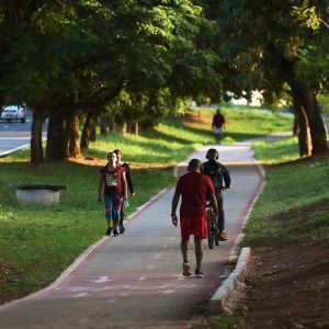 People walking and riding bikes on a bikeway through a park