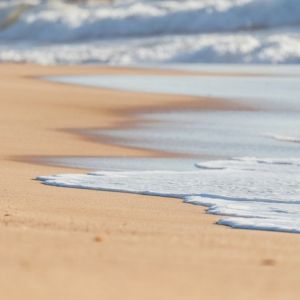 An ocean wave washes over a sandy beach