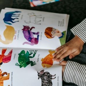 Child holding a picture book with pictures of colorful animals.