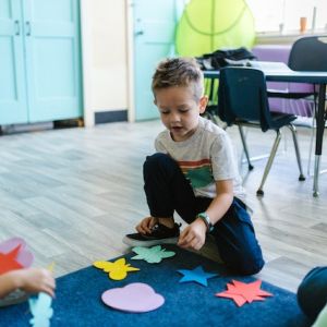 Boy in Gray Crew Neck T-shirt Playing With Blue and Red Puzzle Mat