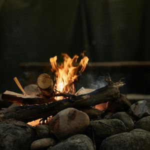 A small campfire sits in the center of rocks against a dark background