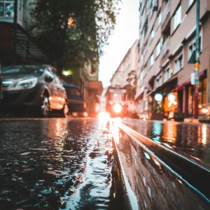 A low view of a city street with water, cars running along it