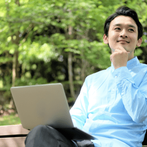Person on bench, trees in background, laptop.