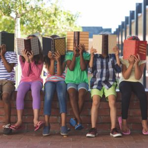 Students sitting and covering faces with books.