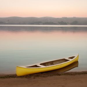 Yellow canoe on the shore of Tomales Bay at dusk with pastel colors and glassy water