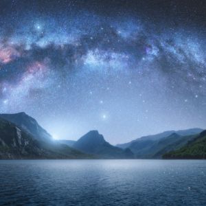 Arched Milky Way over the beautiful mountains and blue sea at night in summer. Colorful landscape with bright starry sky with Milky Way 