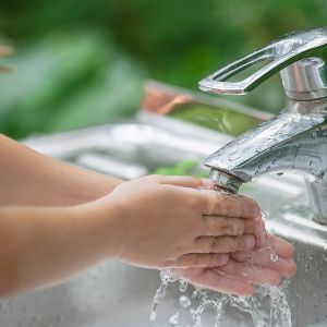 young child's arms and hands washing under faucet