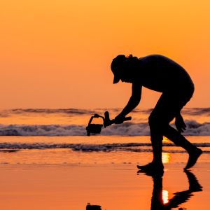 A young and independent filmmaker filming near beach silhouette