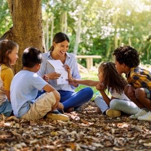 an educator sits in a circle with young kids outside