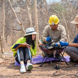 Three scientists in the field examining a rock sample.