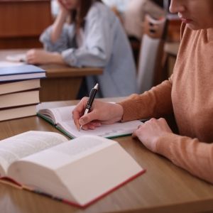 Students sit at desks with book stacks.